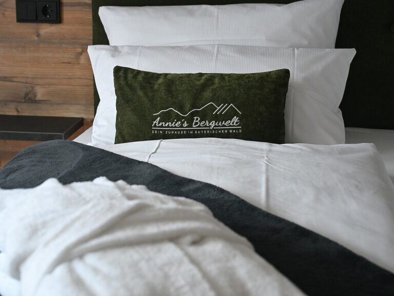 Drei Kissen liegen auf einem gemütlichen Bett mit frischer Bettwäsche.