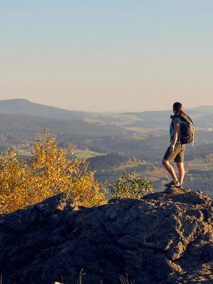Ein Wanderer steht auf einem Felsen und hat einen majestätischen Ausblick auf den Bayerischen Wald