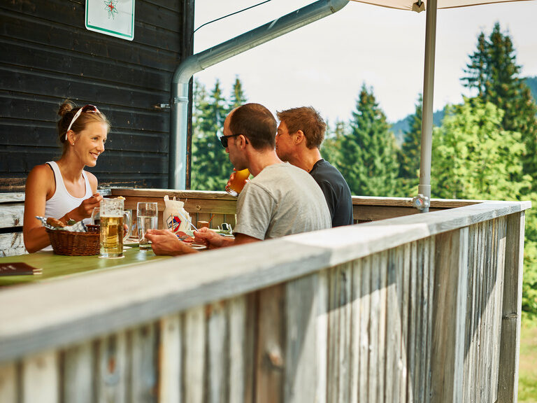 Ene Gruppe sitzt zusammen und macht eine entspannte Wanderpause im Bayerischen Wald.