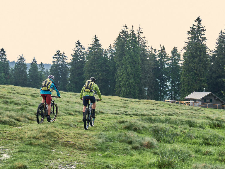 Radfahrer auf dem Weg über ein Feld zu einer Hütte im Bayerischen Wald.